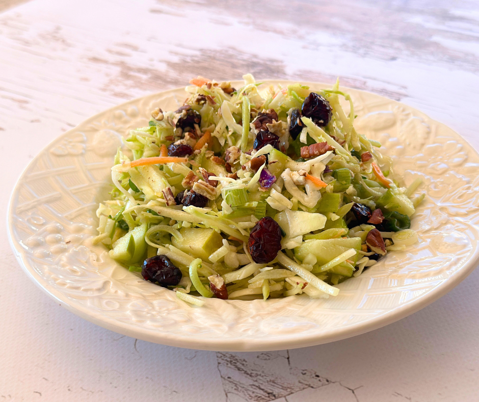 The perfect sweet and tangy slaw with apples, cabbage, and a light vinaigrette. A fresh and colorful Sweet & Tangy Apple Slaw served on a plate, garnished with cranberries and pecans, with a drizzle of apple cider dressing for the perfect balance of sweet and tangy flavors